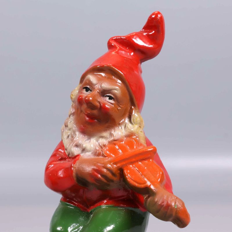 Närbild på tomtefigur med fiol och röd luva