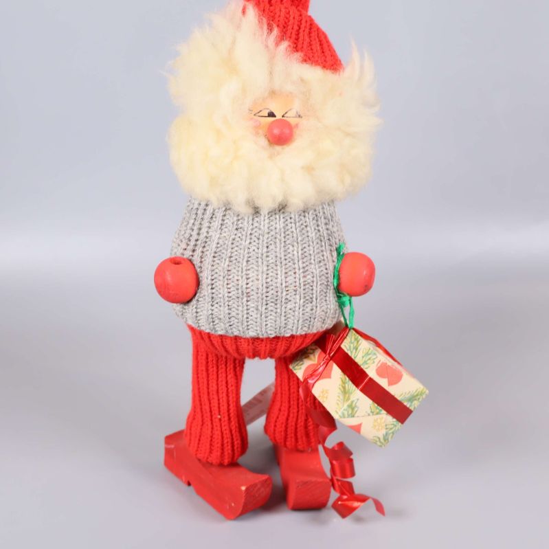 Tomtefigur med present syns framifrån mot ljus bakgrund