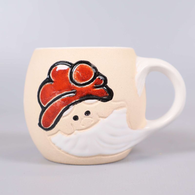 Närbild på mugg med tomtemotiv och röda detaljer