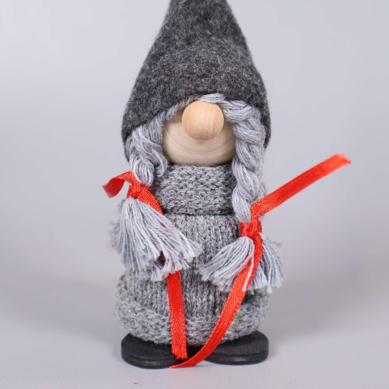 Närbild på tomte med flätor, grå mössa och rött band