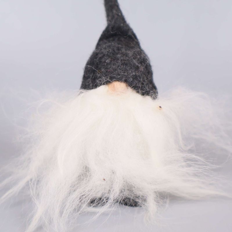 Närbild på tomte med lång vit skägg och grå mössa