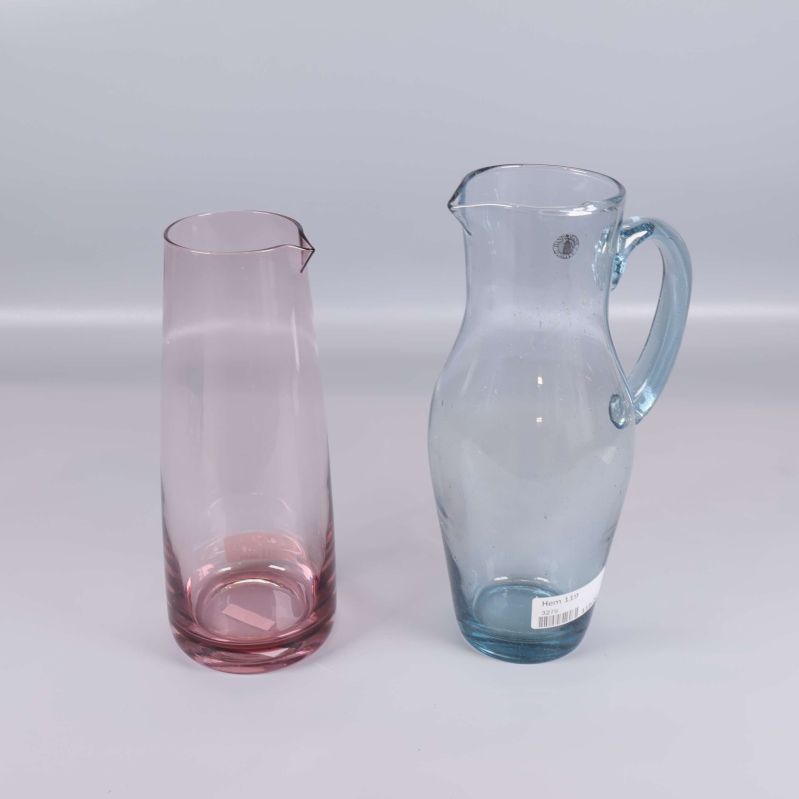 Två kannor i rosa och blått glas i profil