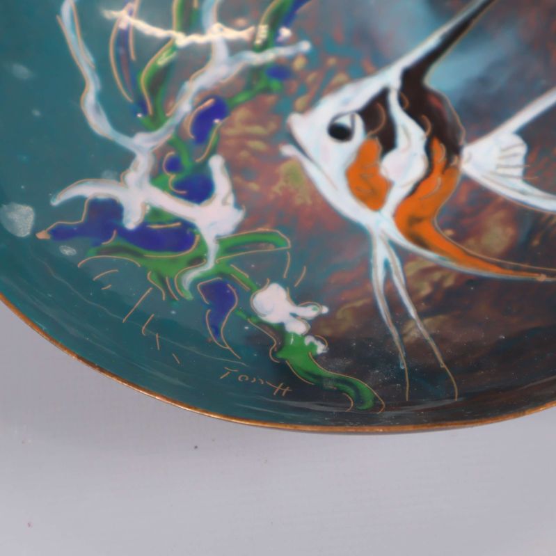 Närbild på signaturen och detaljer av fiskmotivet