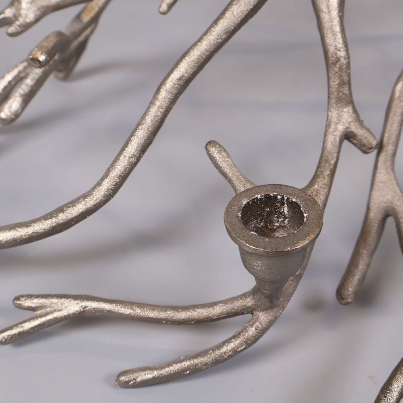 Närbild av ljushållare på silverfärgad grenformad metallstake med strukturerad yta