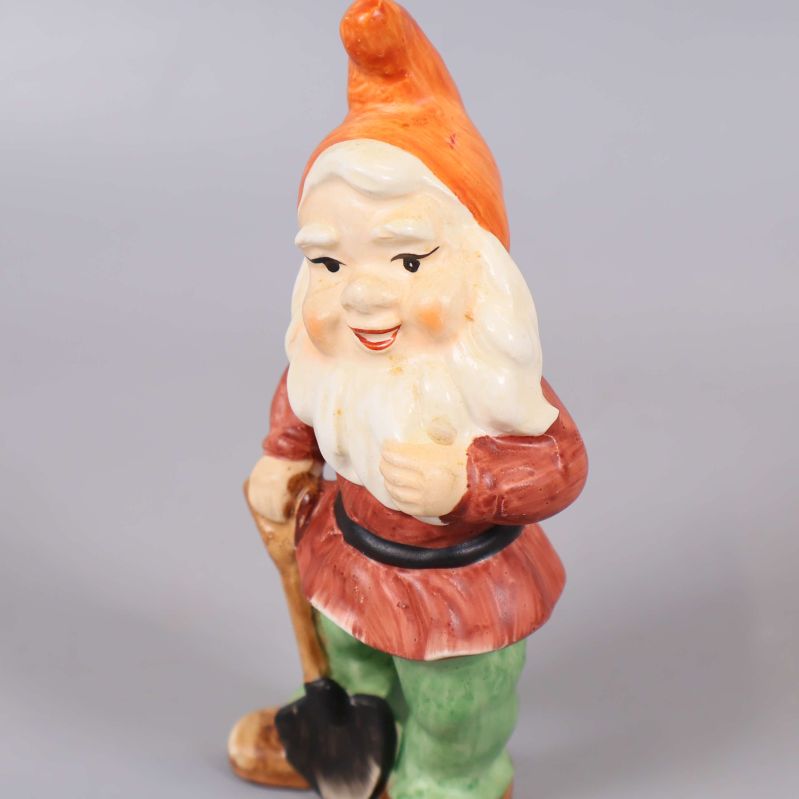 Närbild av tomtefigur med vitt skägg och spade