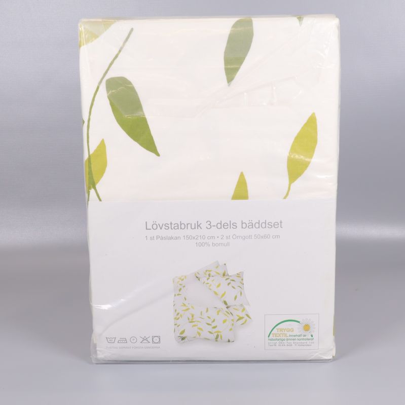 Framsida av förpackat vitt bäddset med gröna blad