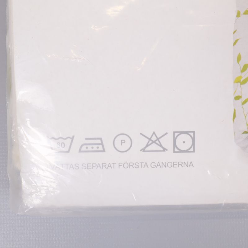 Närbild av tvättrådssymboler på vit bäddsetsförpackning