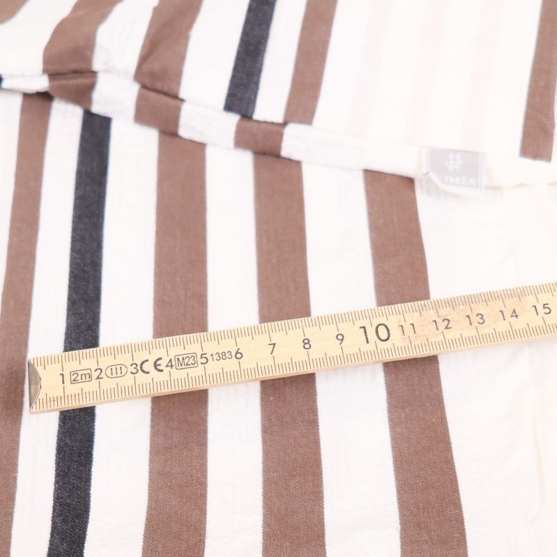 Randigt tyg bredvid tumstock som visar cirka femton centimeter