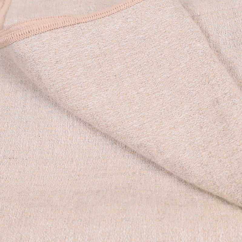 Närbild på ljus melerad textil och rosa kantband