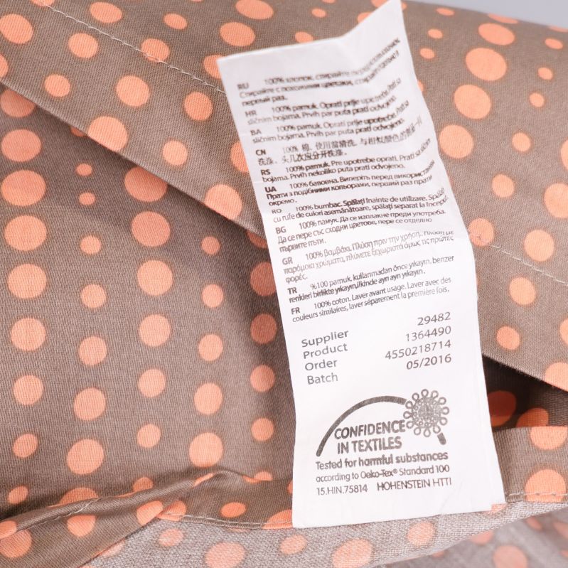 Närbild av etikett med materialinformation på prickigt tyg