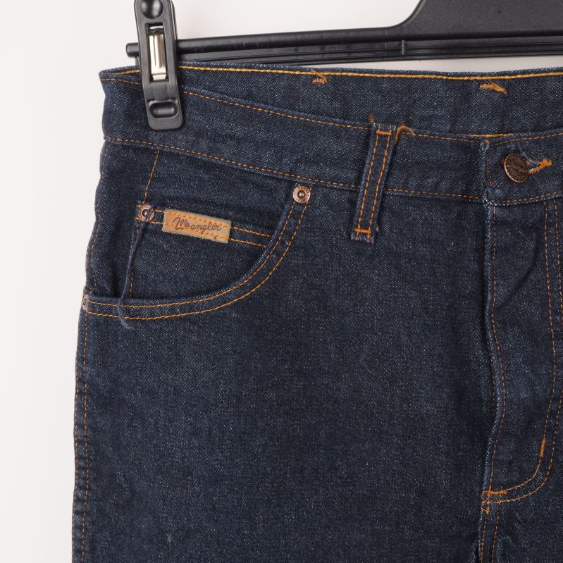 Närbild av övre del av jeans med fickor och knapp