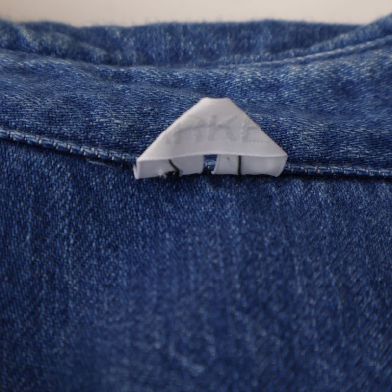 Logotyp på undersida av kragen på denimskjorta
