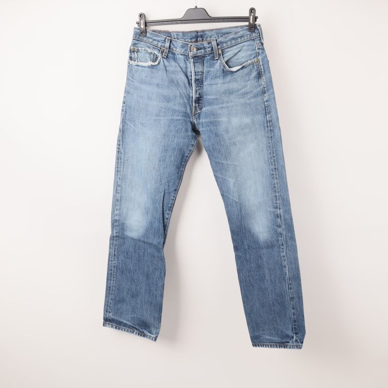 Framsidan av blå jeans med knappgylf och fickor