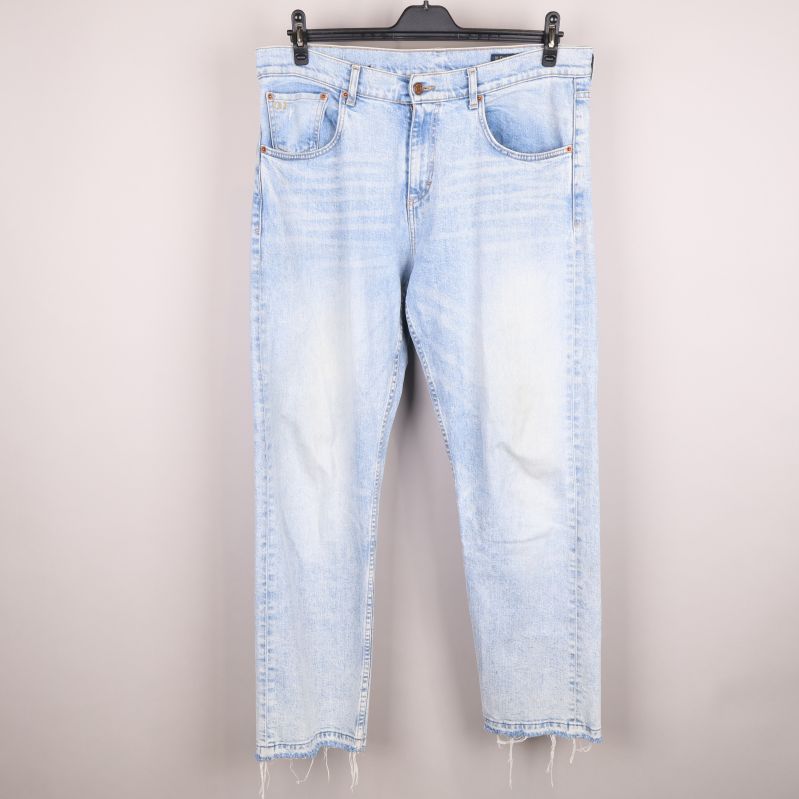 Framsida av ljusa jeans med rå fåll