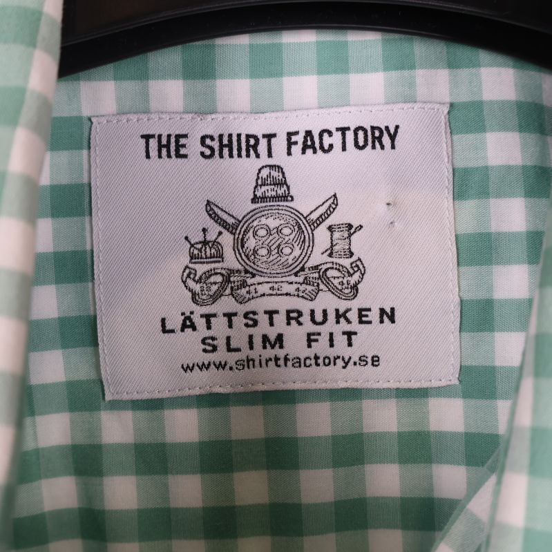 Etikett 'The Shirt Factory' på rutigt tyg