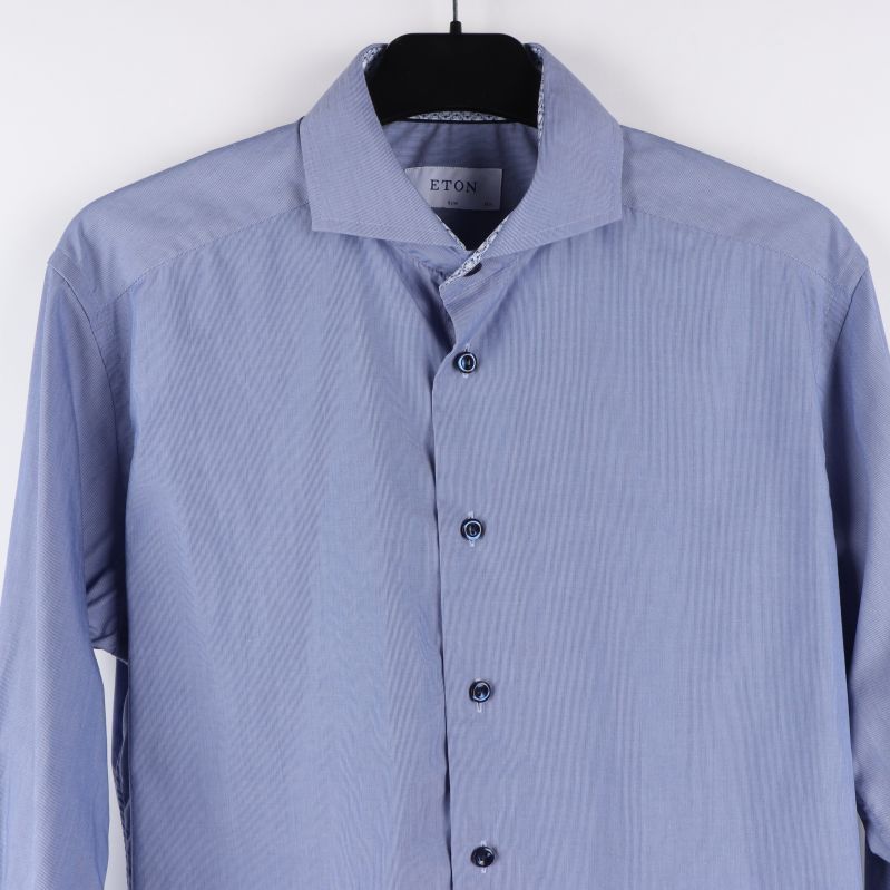 Närbild på krage och knappar på ljusblåa skjortan