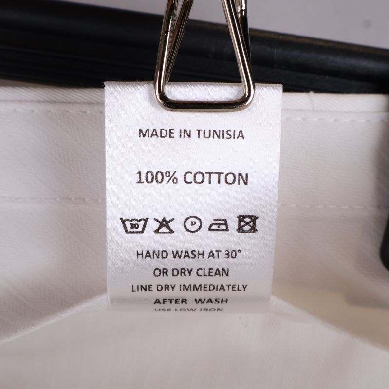 Vit tvättrådsetikett med materialinformation