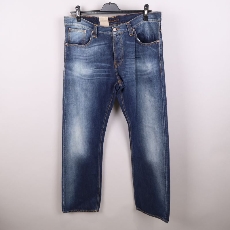 Framsida av mörkblå jeans med slitningar