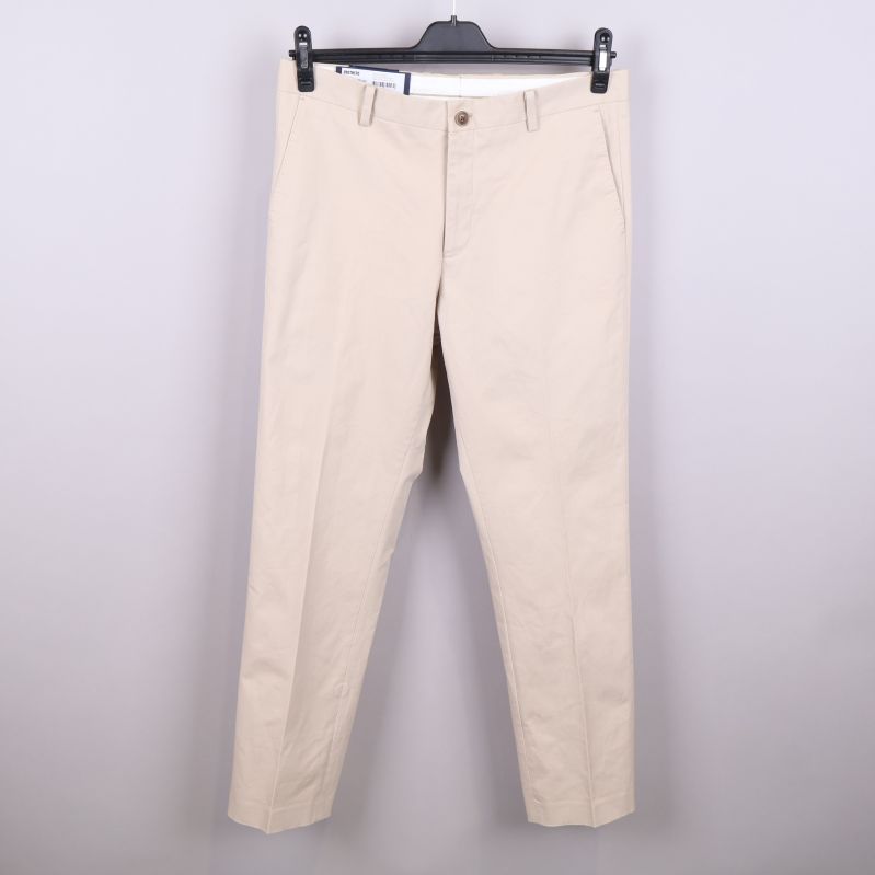 Framsidan av beige chinos med knapp