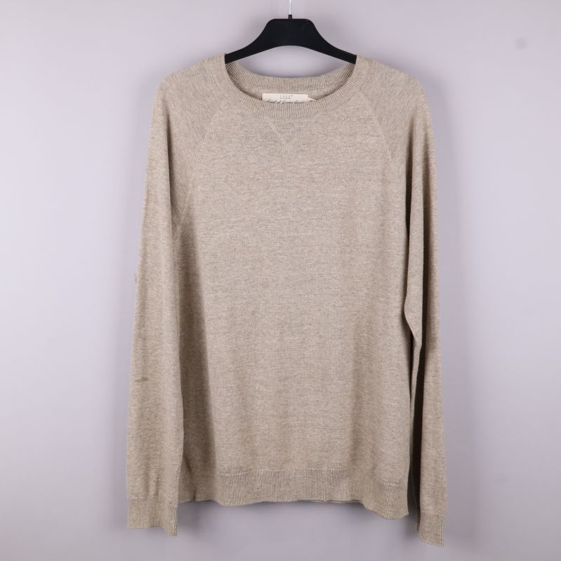 Framsidan av beige stickad tröja
