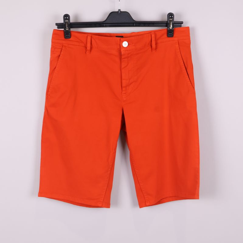 Orange shorts framifrån med fickor och knapp