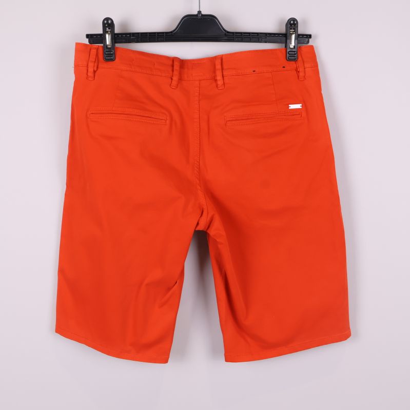 Orange shorts bakifrån med bakfickor och etikett