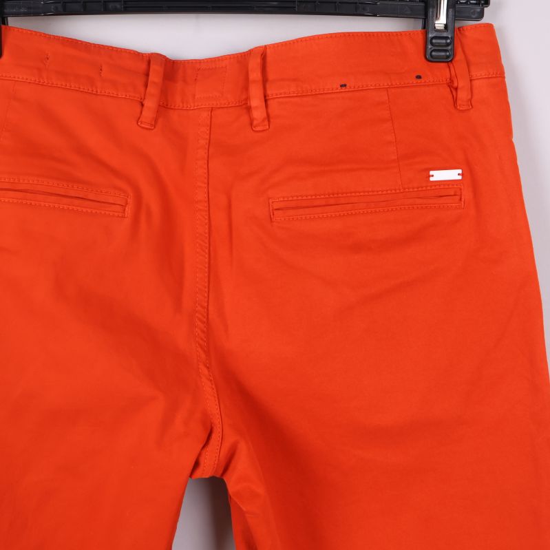 Närbild på bakficka och midja på orange shorts