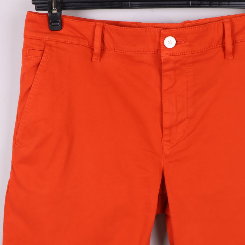 Närbild på midjan och framfickor på orange shorts