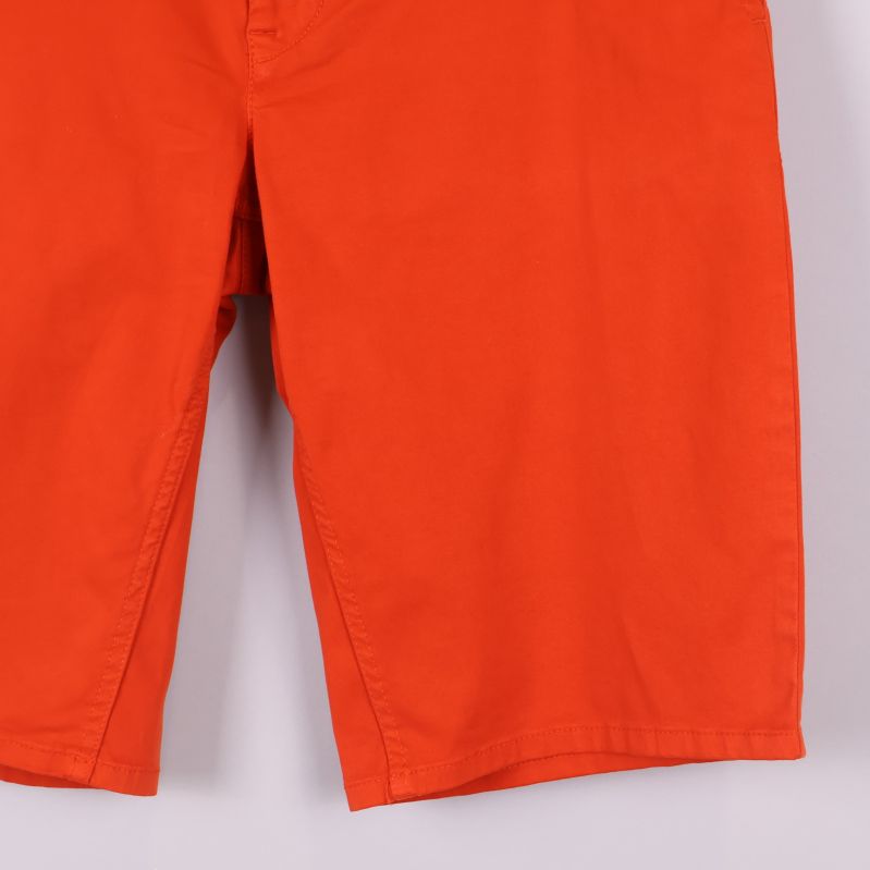 Närbild på bensluten av orange shorts