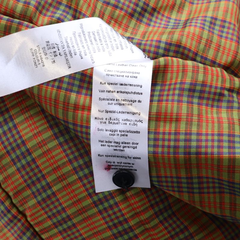 Materialetikett med skötselråd inuti jacka mot rutigt foder