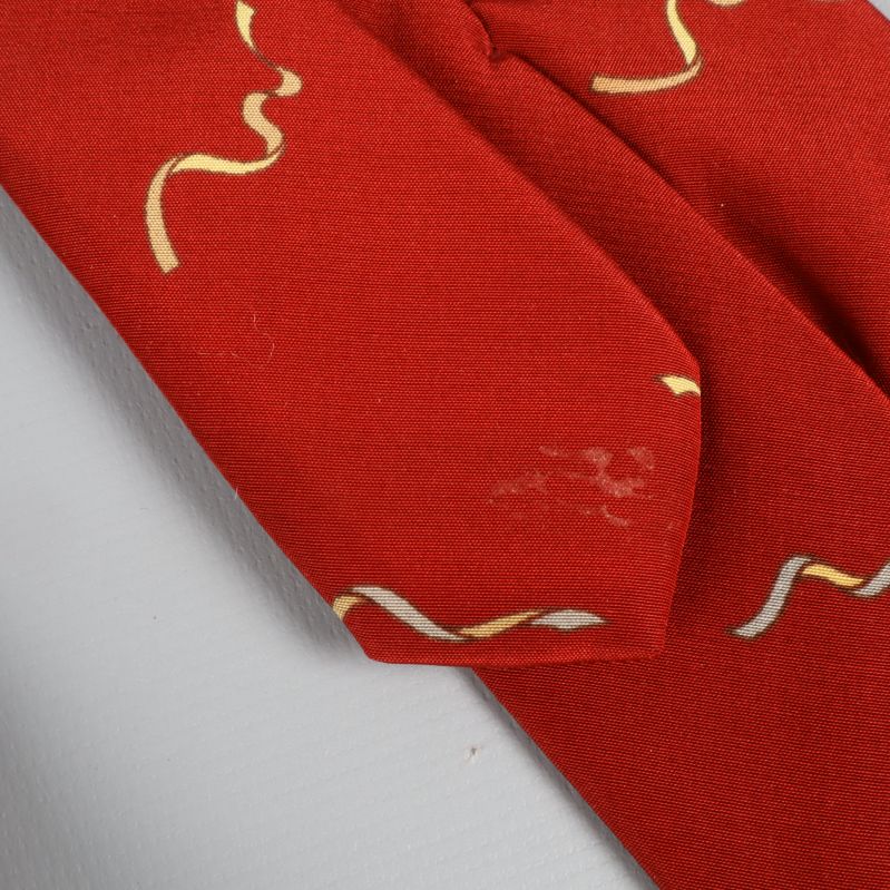 Röd slips rullad ihop med gulmönster synligt