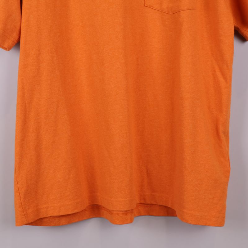 Nederkant på orange t-shirt visas i detalj