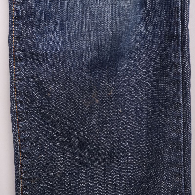 Närbild på jeanstyg med lätt slitage och tvätteffekt