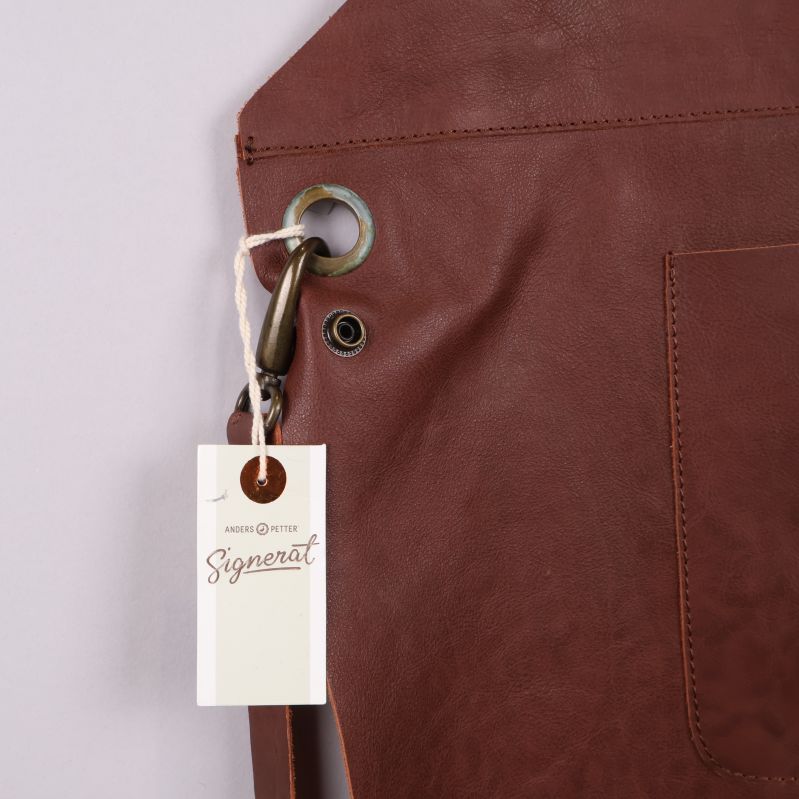 Närbild på metallring och etikett vid förklädets hörn