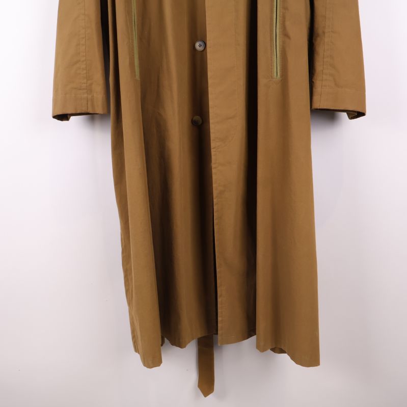 Nedre del av brun trenchcoat med bältets ände synlig