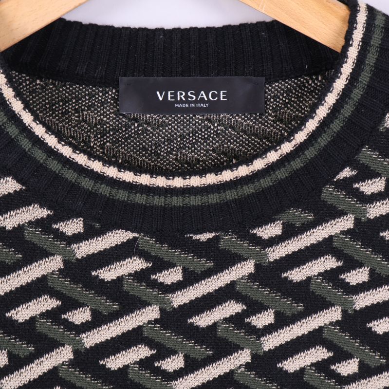 Närbild på Versace-logotyp vid kragen och stickat mönster