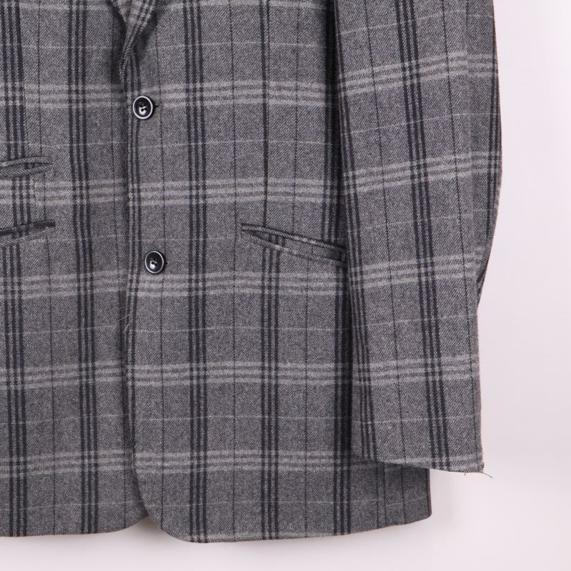 Kavajens högra ärm och ficka i rutigt tyg