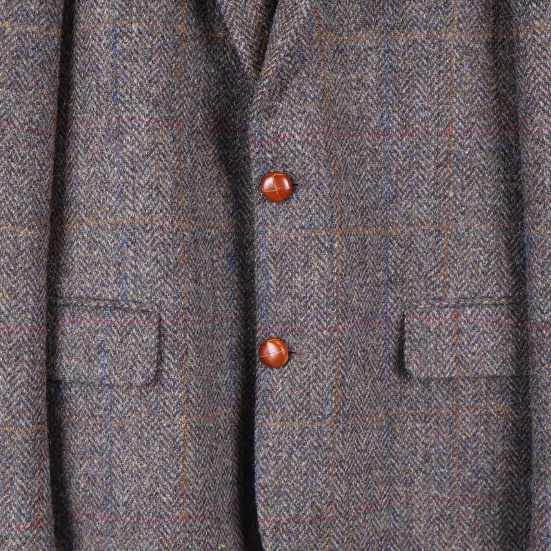 Närbild på rutmönstrad tweed och bruna knappar