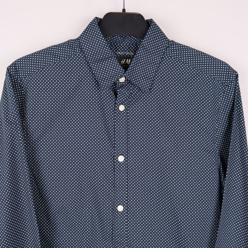 Närbild krage och översta knappar på prickig skjorta