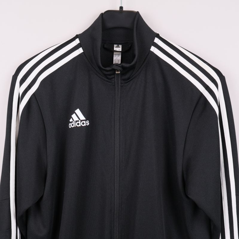 Närbild bröst på svart Adidasjacka med logga