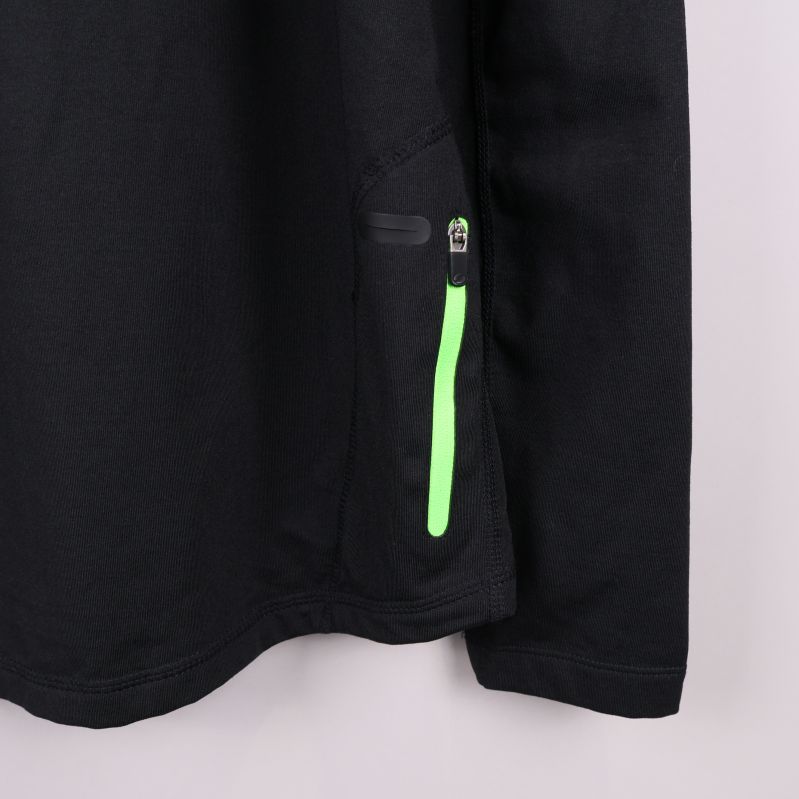 Närbild på neongrön dragkedja i sidan av tröjan