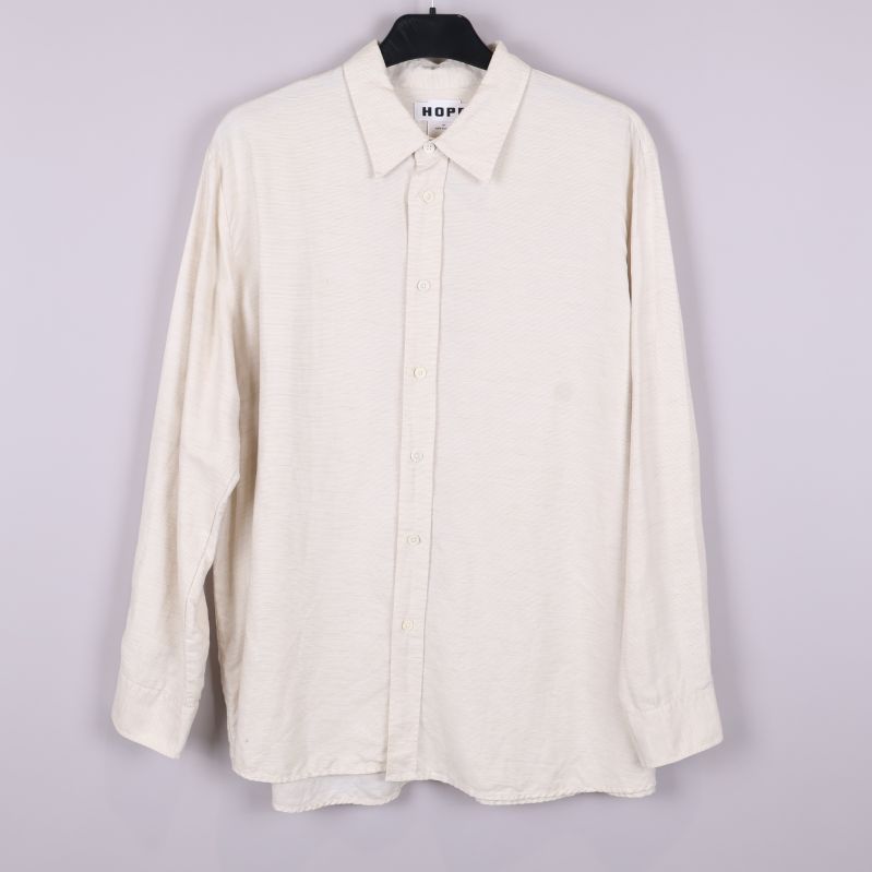 Beige skjorta med långa ärmar och krage hängande på galge