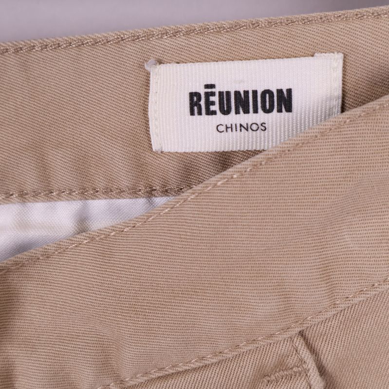Etikett i midjan med texten REUNION CHINOS