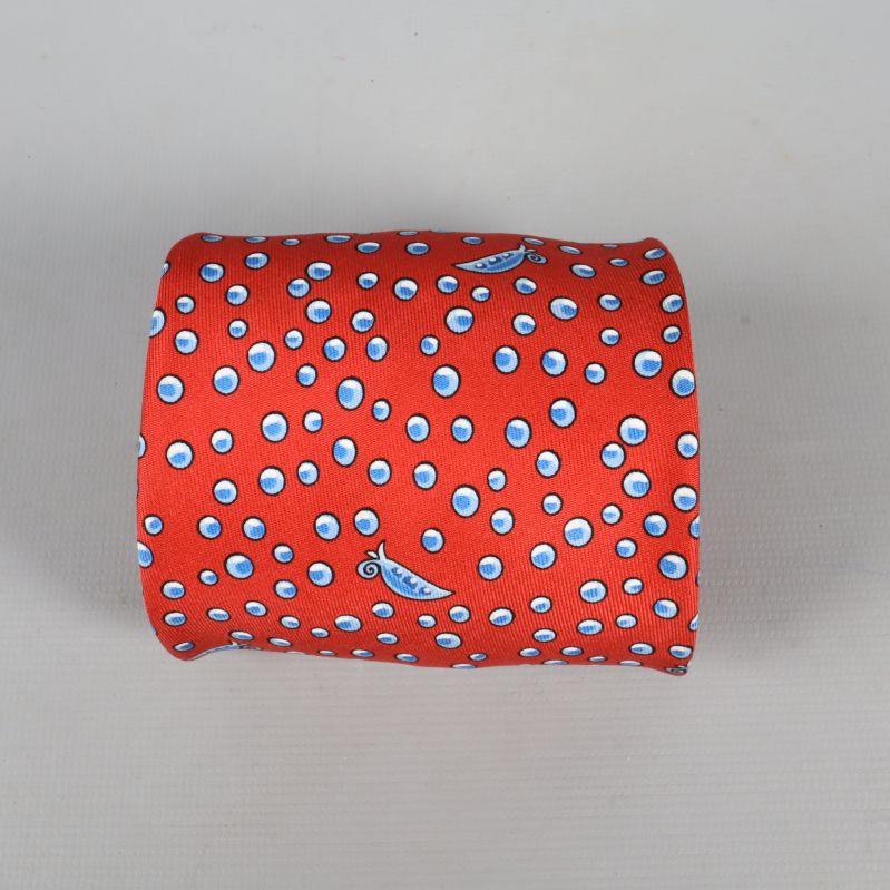 Närbild av mönster på röd Hermès-slips med blå prickar