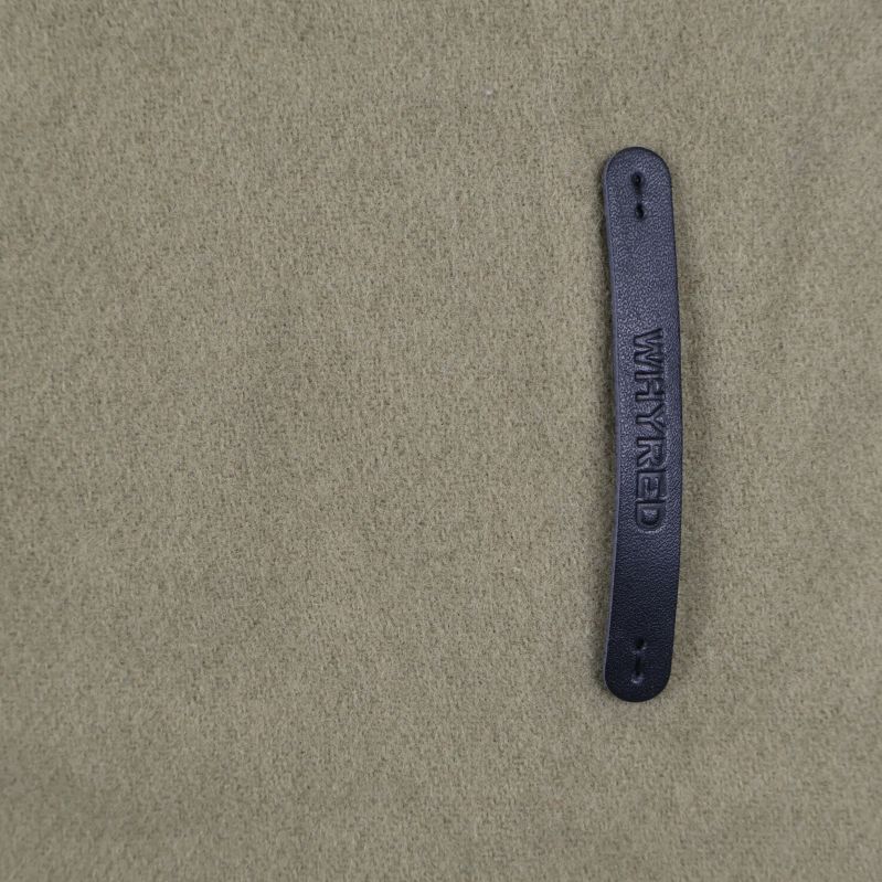 Detaljbild på skinnmärke med text på halsduk