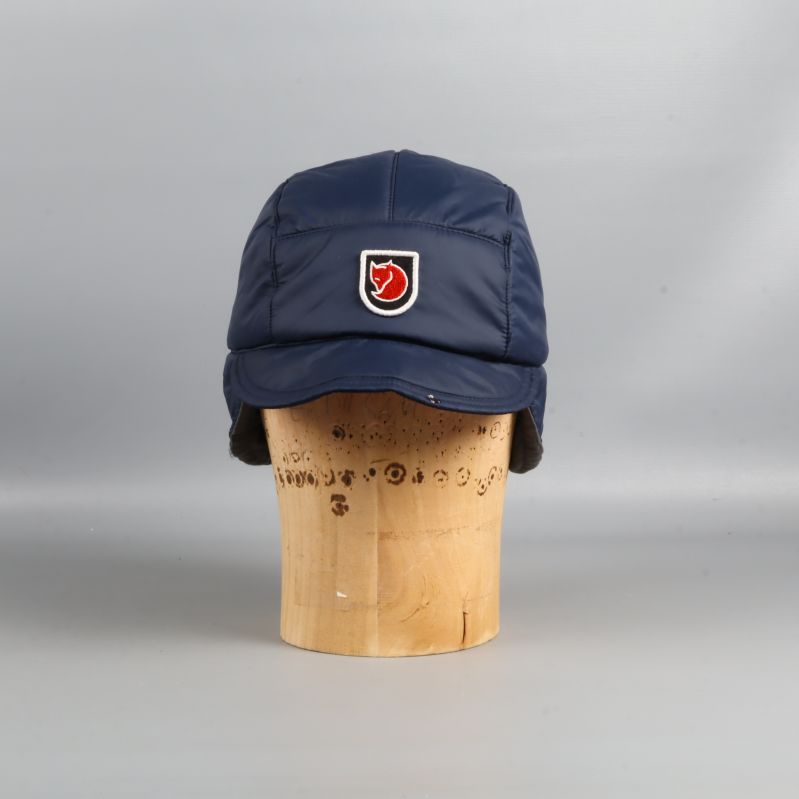 Blå vadderad keps med öronlappar sedd framifrån med logga