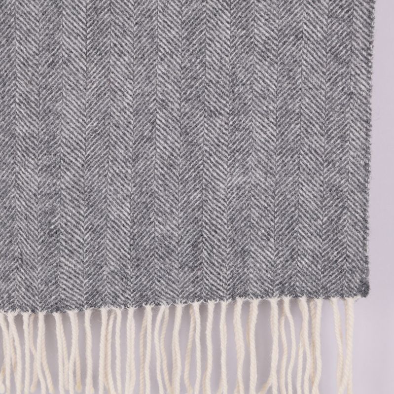 Närbild på grå fiskbensmönstrad halsduk med fransar