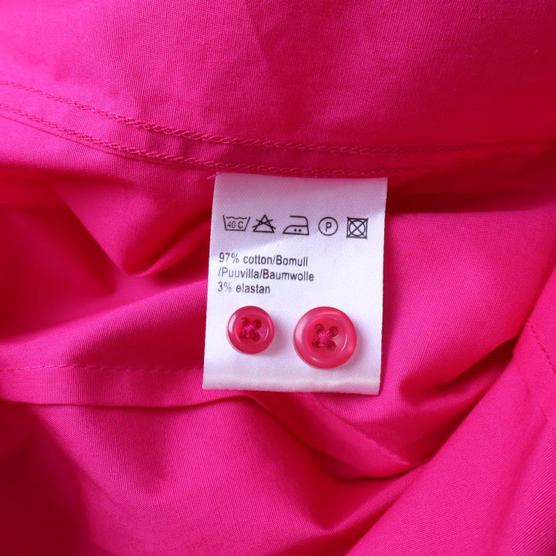 Tvättrådsetikett med materialinfo på kritrosa skjorta