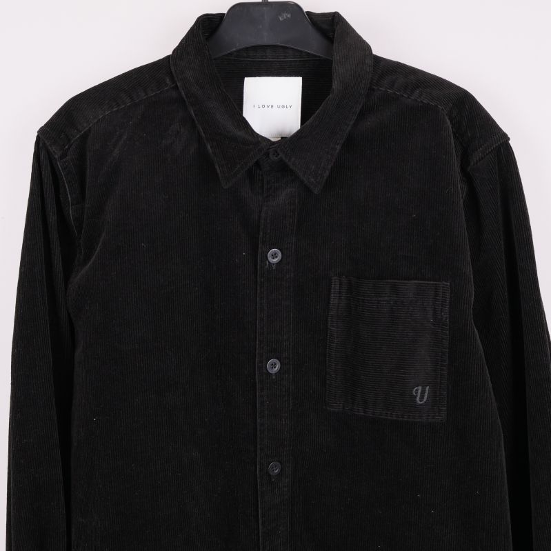 Närbild av bröstficka med broderad detalj på svart overshirt