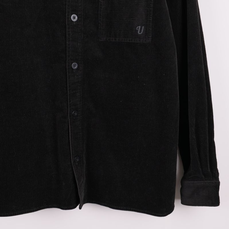 Nedre delen av overshirten i svart manchester med knäppning